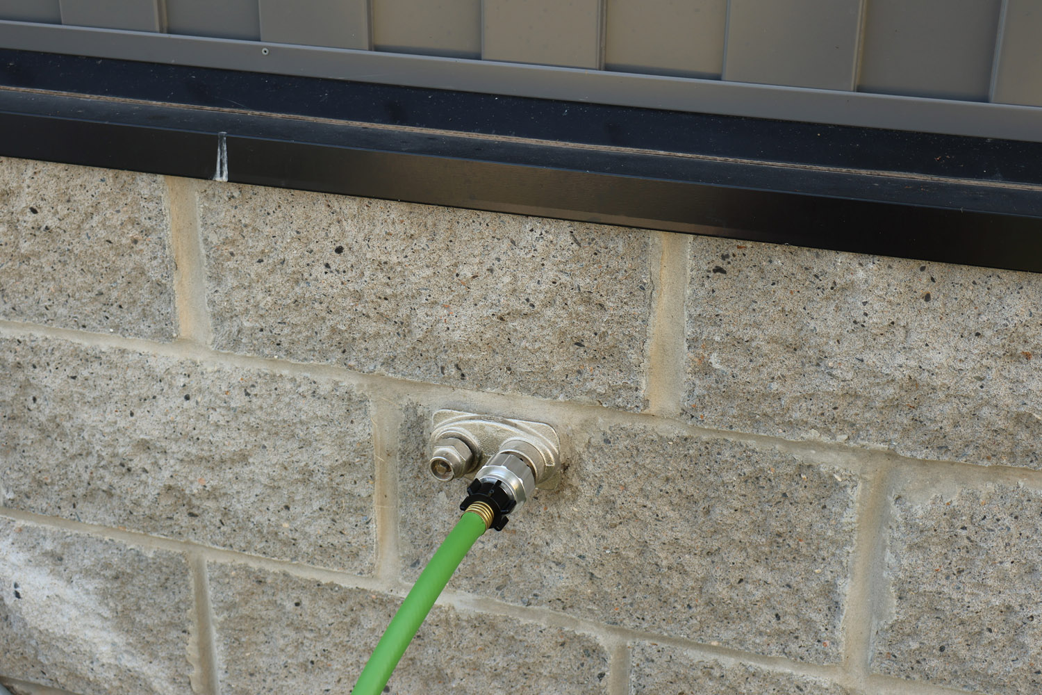 Hose Shark connector mounted on home siding faucet